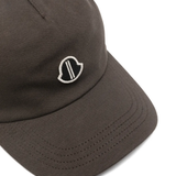 Close up of brown cap, showing the logo detail and the texture of cotton fabric