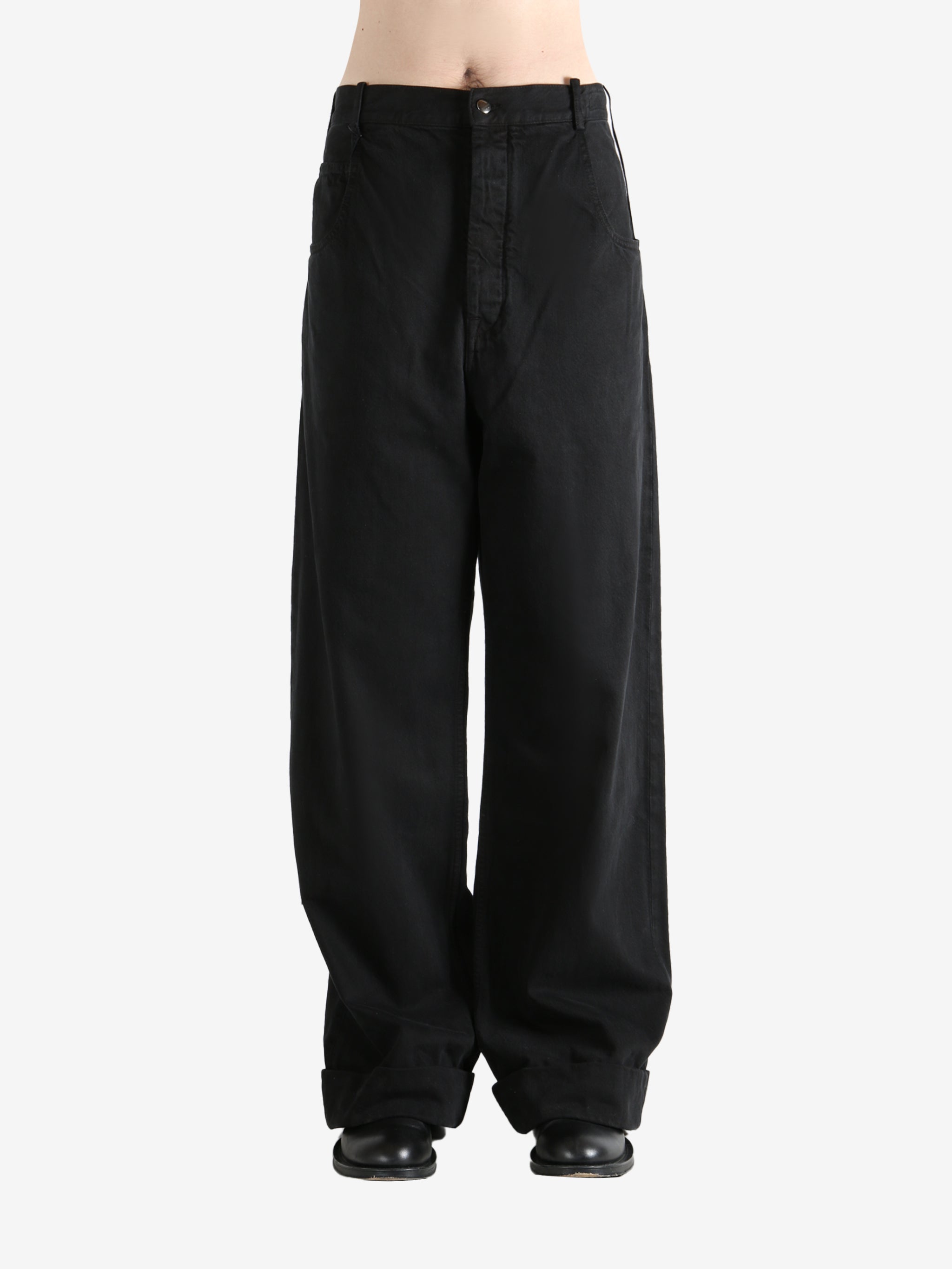 Black trousers worn by a person, showing the trousers fit