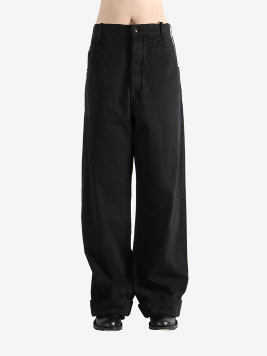 Black trousers worn by a person, showing the trousers fit