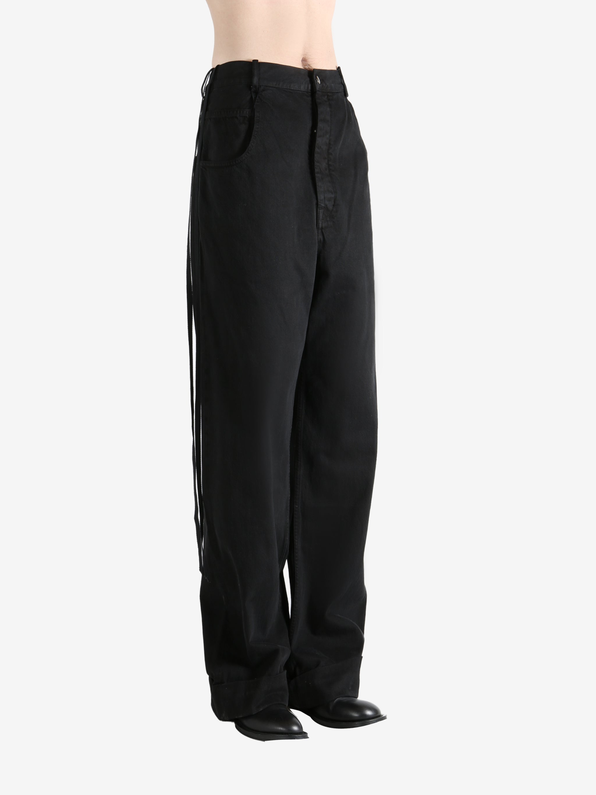 Black trousers worn by a person, showing the trousers fit