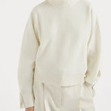 White knitwears worn by a person, showing the knitwears fit