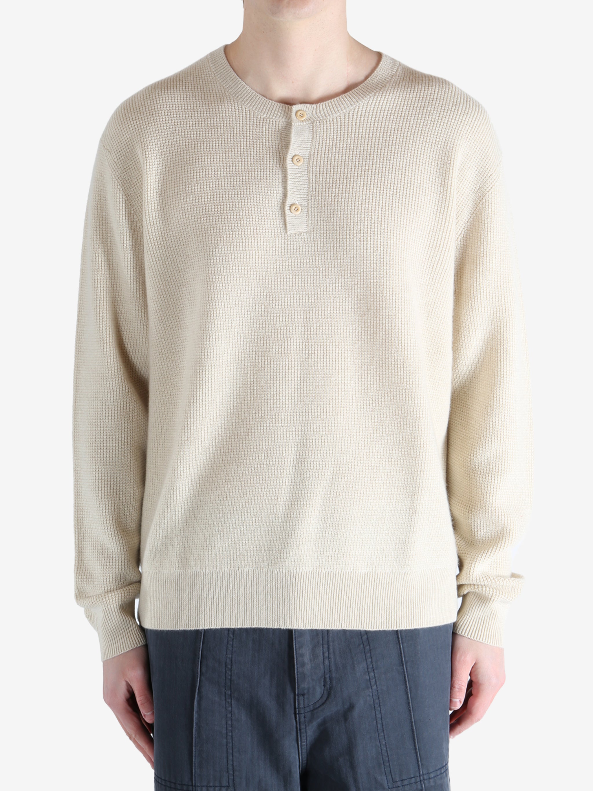 Beige sweater worn by a person, showing the knitwear fit