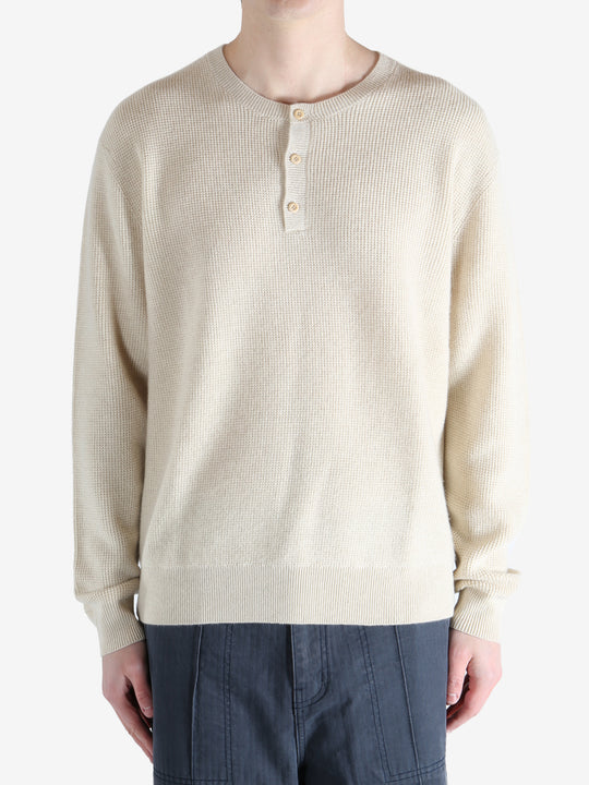 Beige sweater worn by a person, showing the knitwear fit