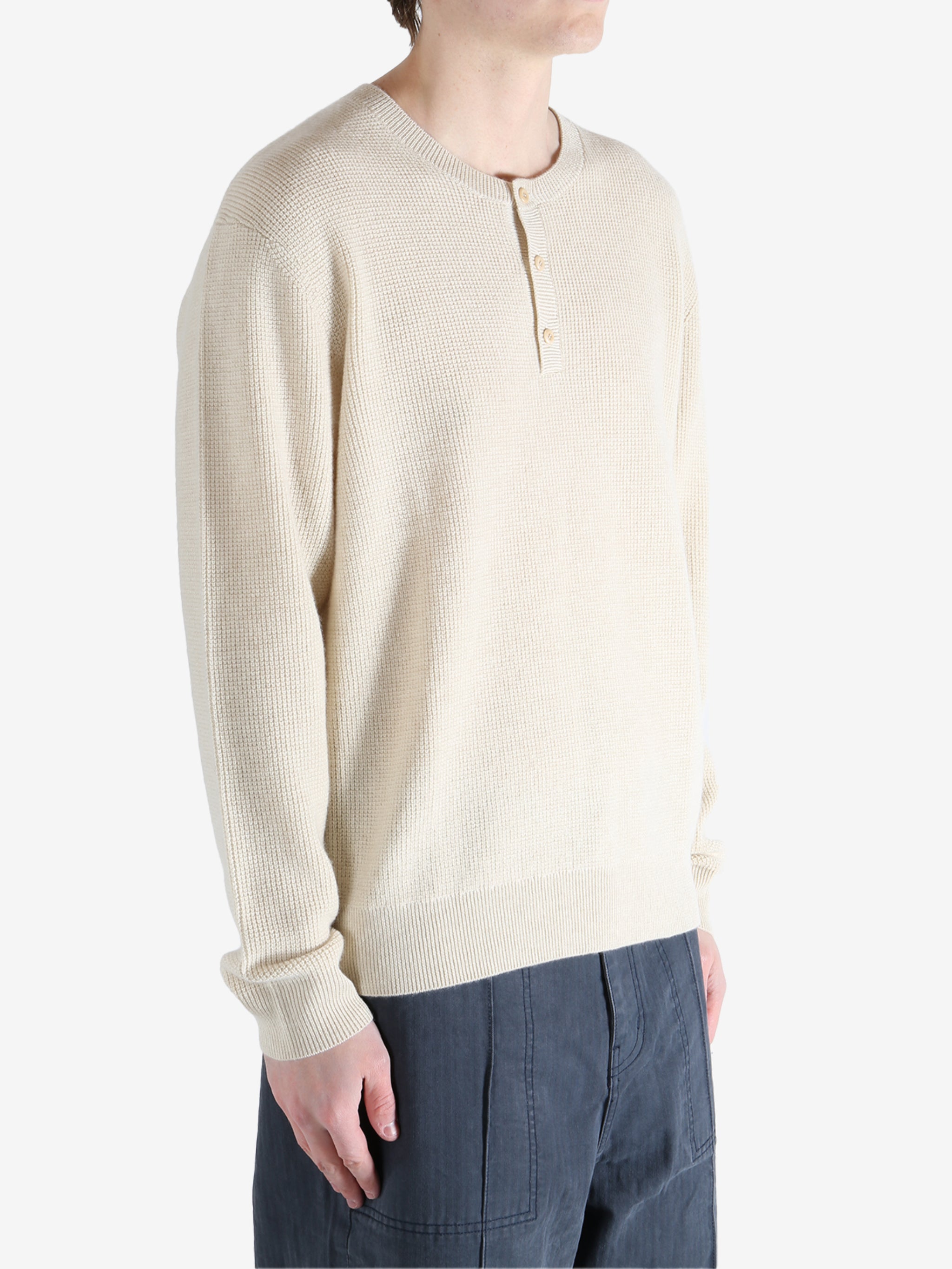 Beige sweater worn by a person, showing the knitwear fit