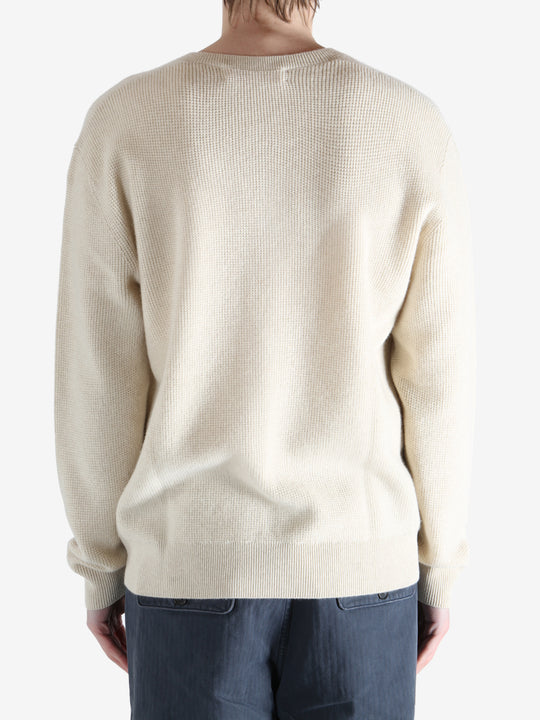 Beige sweater worn by a person, showing the knitwear fit
