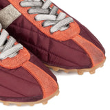 Close up of the red sneakers, showing texture of the suede and polyester fabric