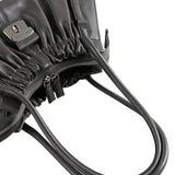 Close-up of a black leather bag with a visible brand logo on a white background