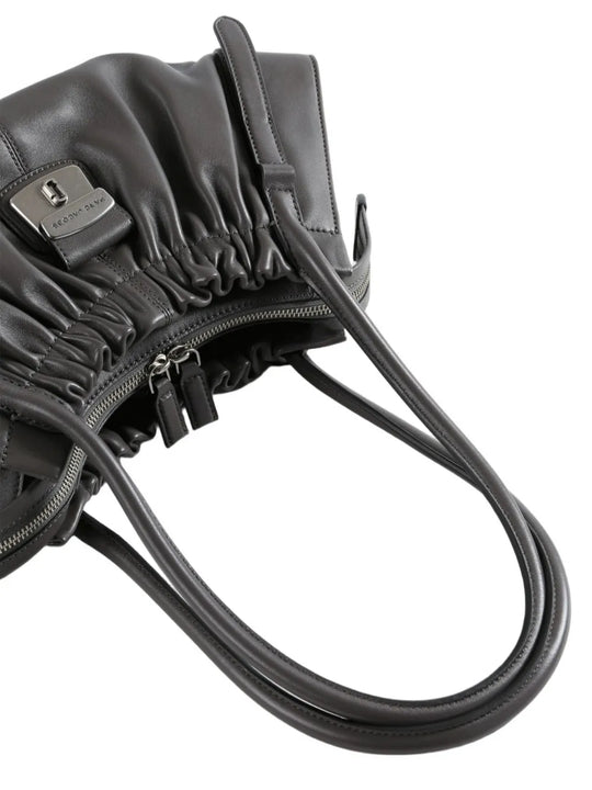 Close-up of a black leather bag with a visible brand logo on a white background