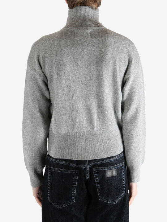 gray zip-up sweater worn by a person, showing the sweater fit