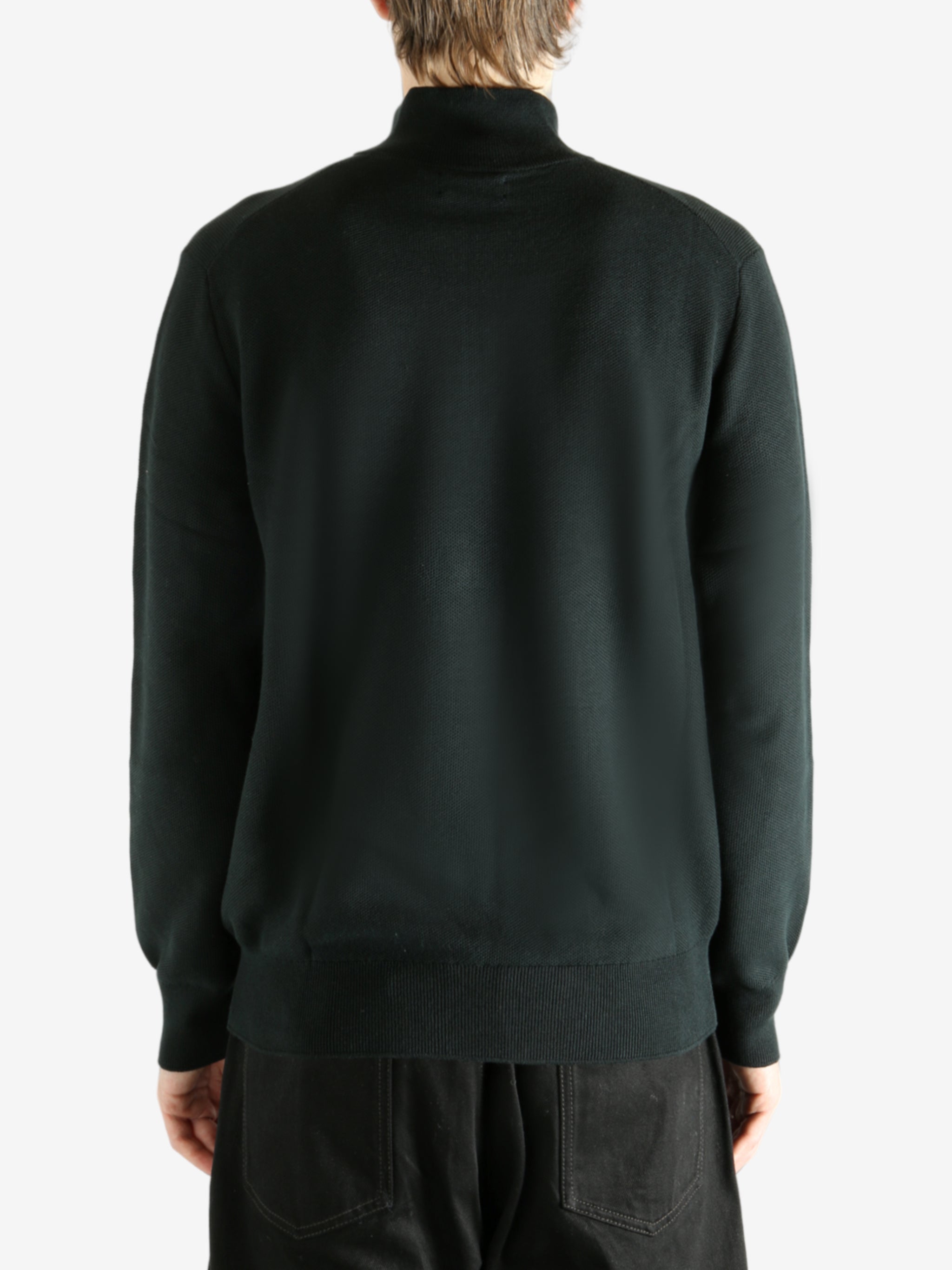 Black knitwear worn by a person, showing the knitwear's fit