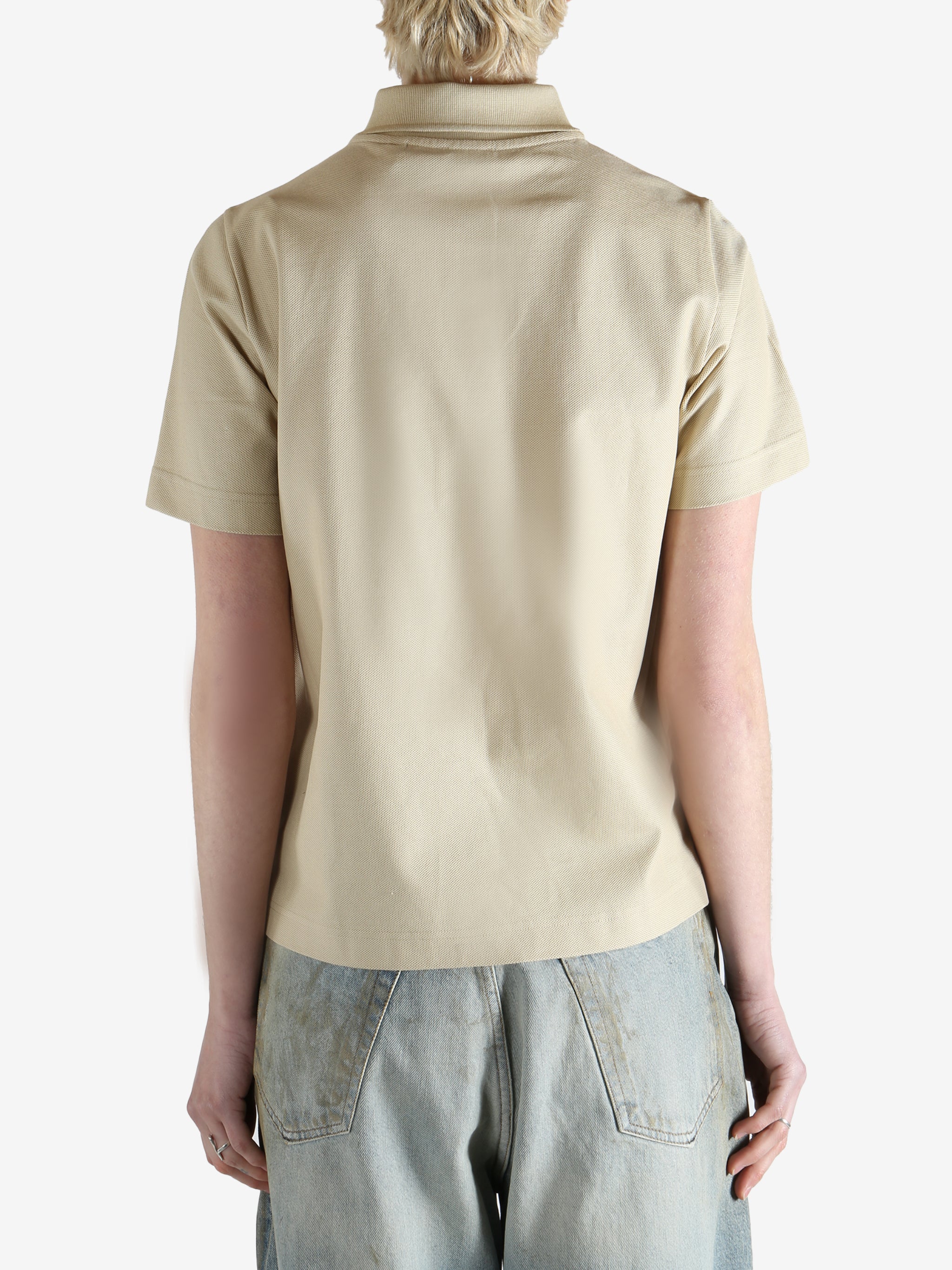 Beige polo shirt worn by a person, showing the shirt fit