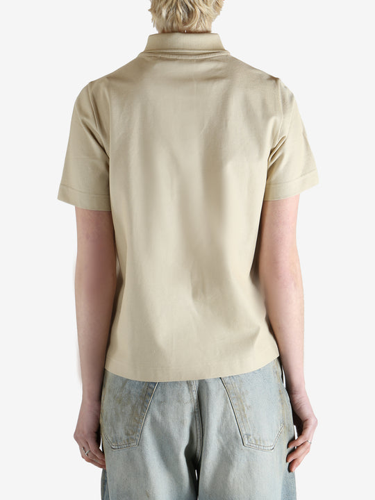 Beige polo shirt worn by a person, showing the shirt fit