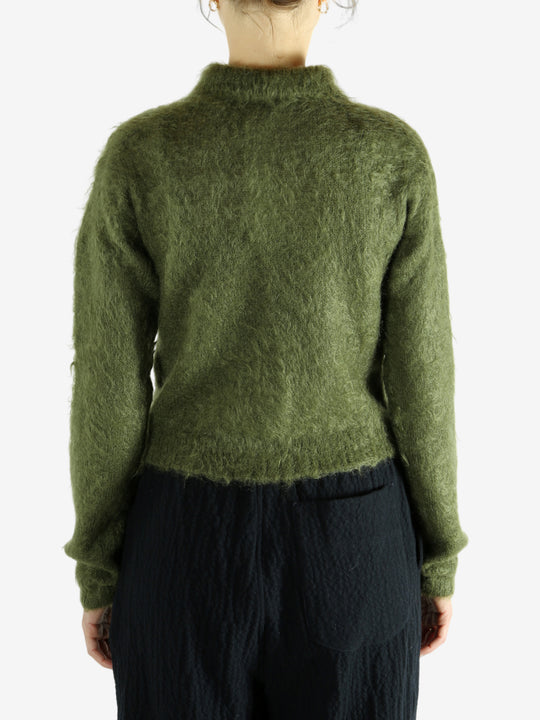 Green knitwear worn by a person, showing the knitwear's fit