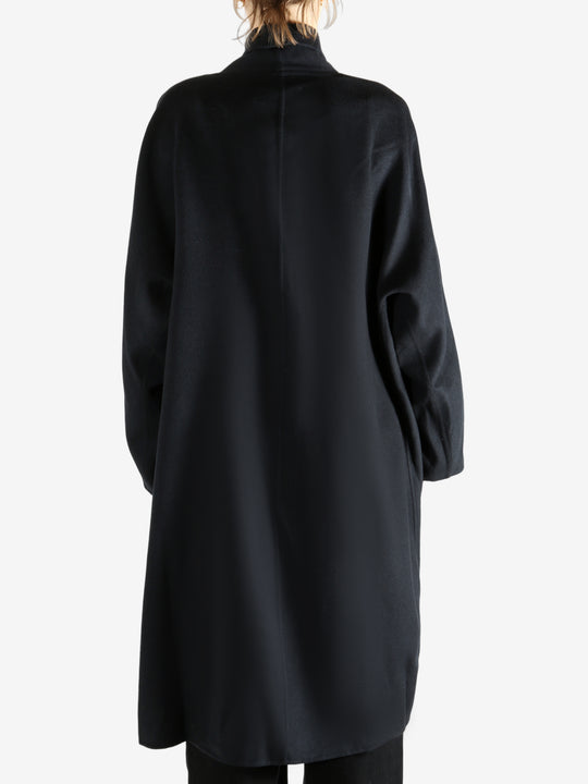 Black coat worn by a person, showing the coat fit