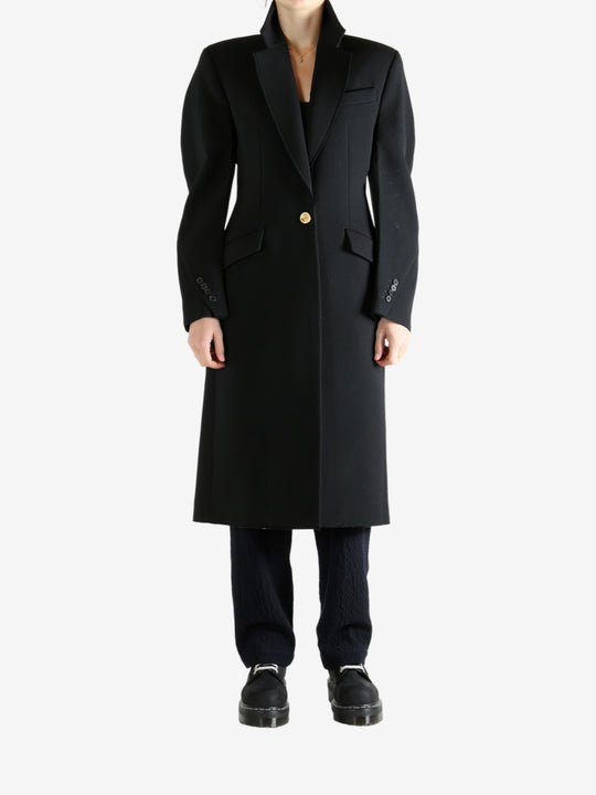 Black coat worn by a person, showing the coat fit