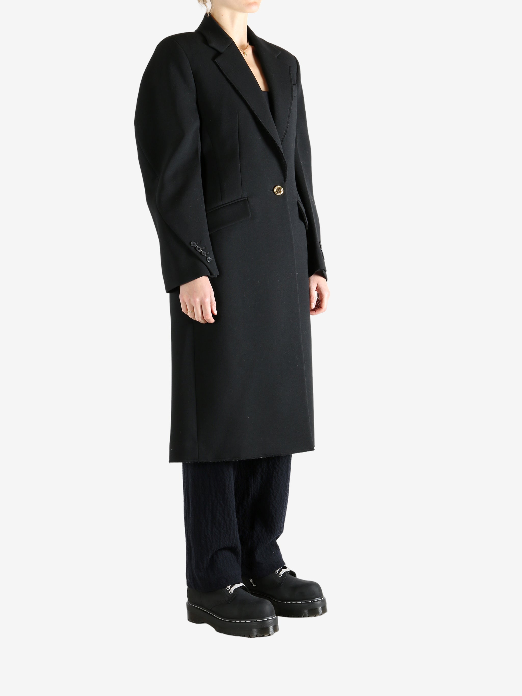 Black coat worn by a person, showing the coat fit