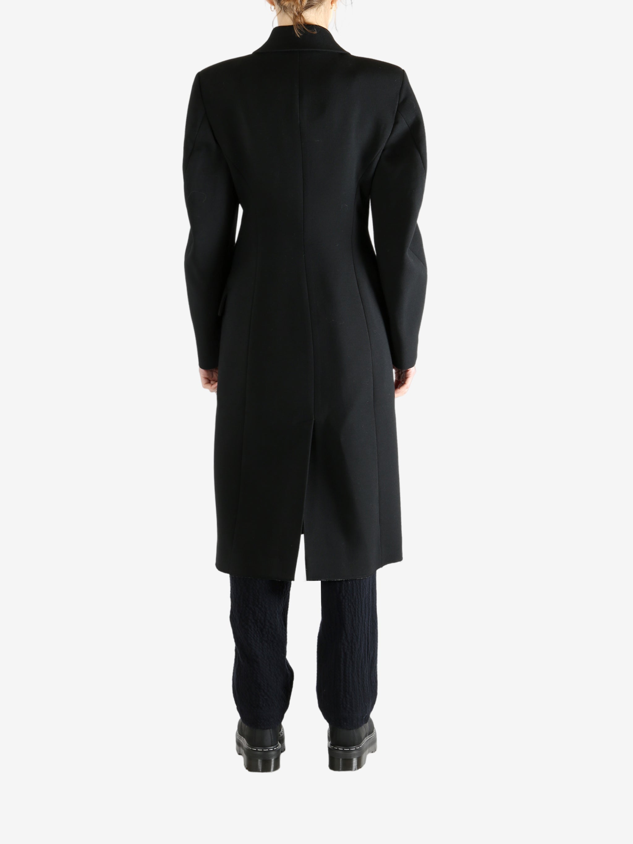 Black coat worn by a person, showing the coat fit