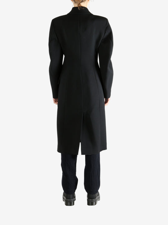 Black coat worn by a person, showing the coat fit