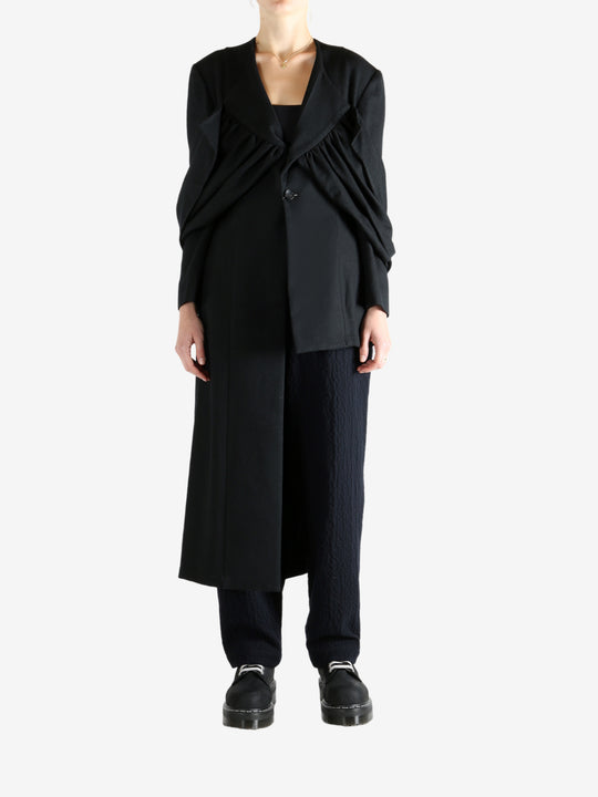 Black coat worn by a person, showing the coat fit