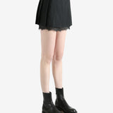 black pleated skirt worn by a person, showing the skirt fit