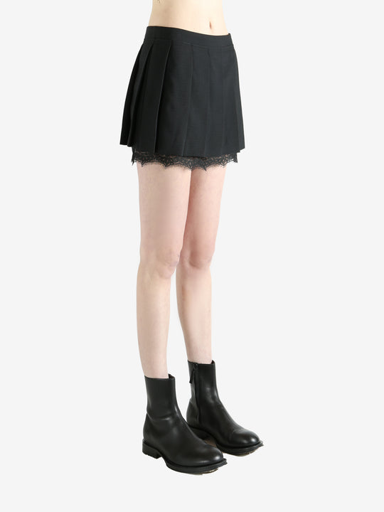 black pleated skirt worn by a person, showing the skirt fit