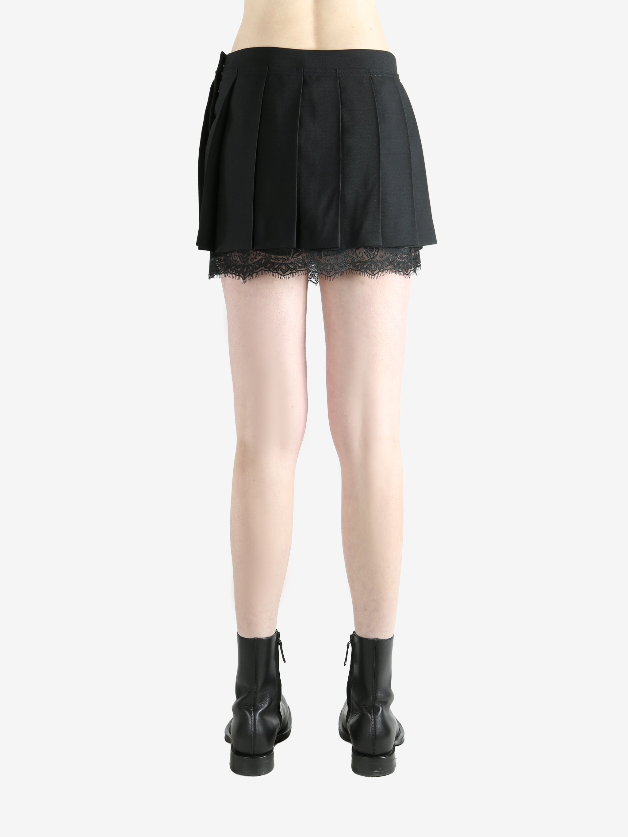 black pleated skirt worn by a person, showing the skirt fit