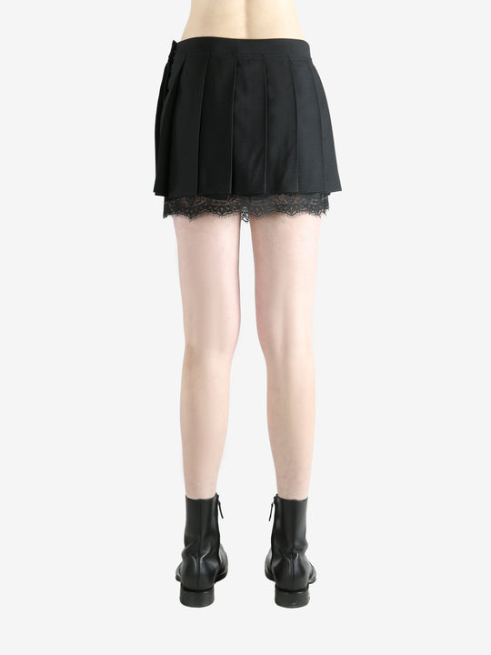 black pleated skirt worn by a person, showing the skirt fit