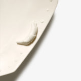 Detail of JINJIN PARIS Croissant Octagon Plate with sculpted croissant accent and porcelain bead edging.