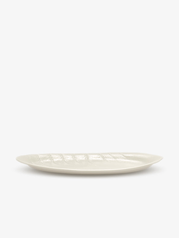 JINJIN PARIS Leaf Oval Plate in ivory porcelain, side view with shallow profile and embossed leaf texture.