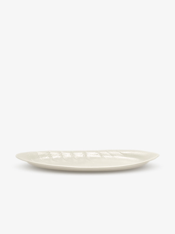JINJIN PARIS Leaf Oval Plate in ivory porcelain, side view with shallow profile and embossed leaf texture.