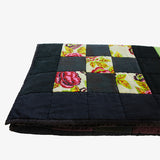 Folded view of Lily Raskind patchwork quilt displaying quilt thickness and floral square detail.