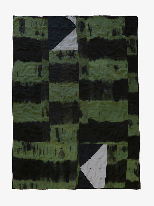 Back view of hand-dyed patchwork quilt by Lily Raskind in green and black tones with abstract panel layout, shown flat.
