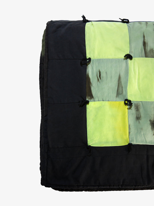 Detail view of Lily Raskind patchwork quilt showing green and black hand-dyed squares with hand-tied stitching.