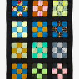 Granny Square quilt with bright multicolor patchwork on black, handmade by Lily Raskind.