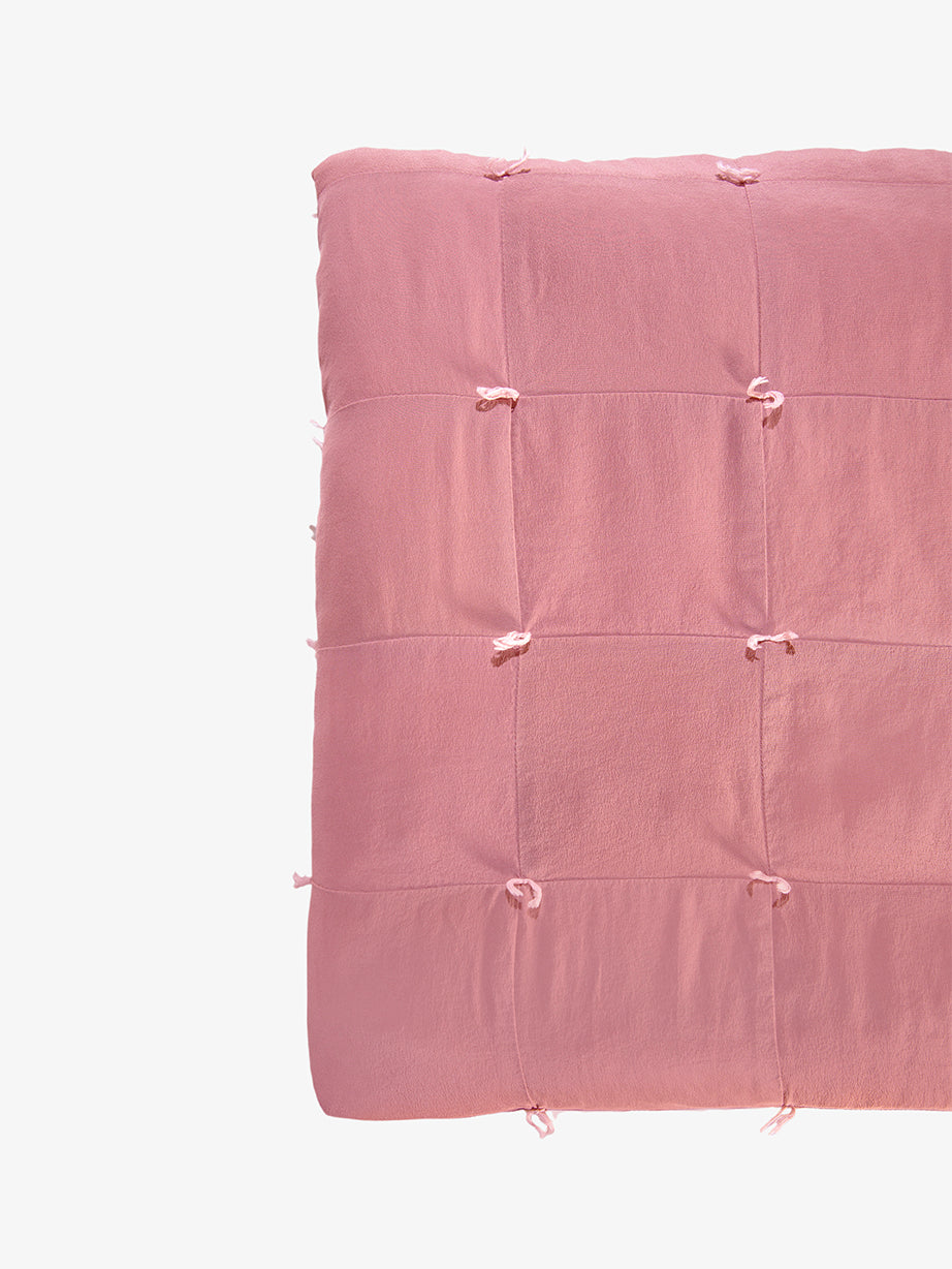 Silk quilt detail in dusty rose showing hand-tied knots and patchwork seams by Lily Raskind.