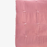 Silk quilt detail in dusty rose showing hand-tied knots and patchwork seams by Lily Raskind.