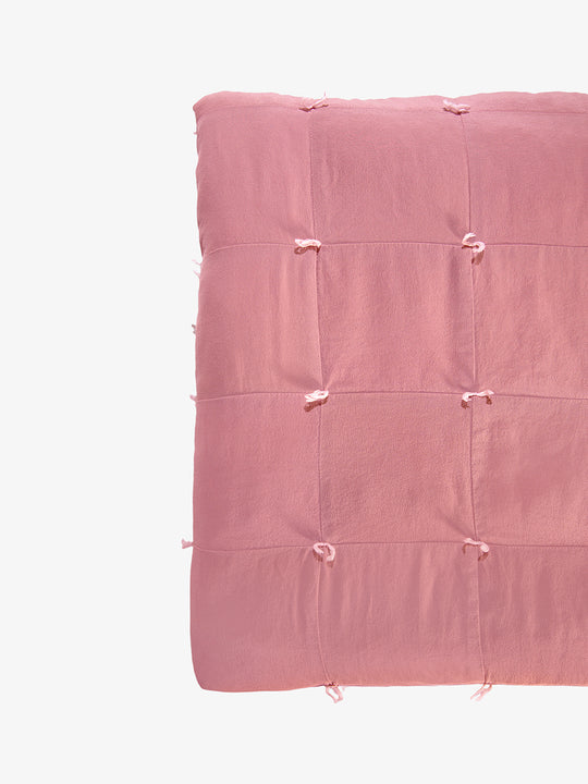Silk quilt detail in dusty rose showing hand-tied knots and patchwork seams by Lily Raskind.