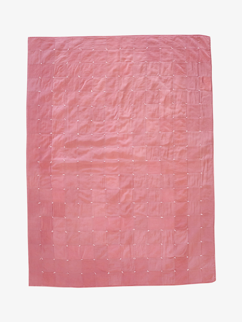 Hand-dyed dusty rose silk patchwork quilt by Lily Raskind, shown flat with square grid stitching detail.
