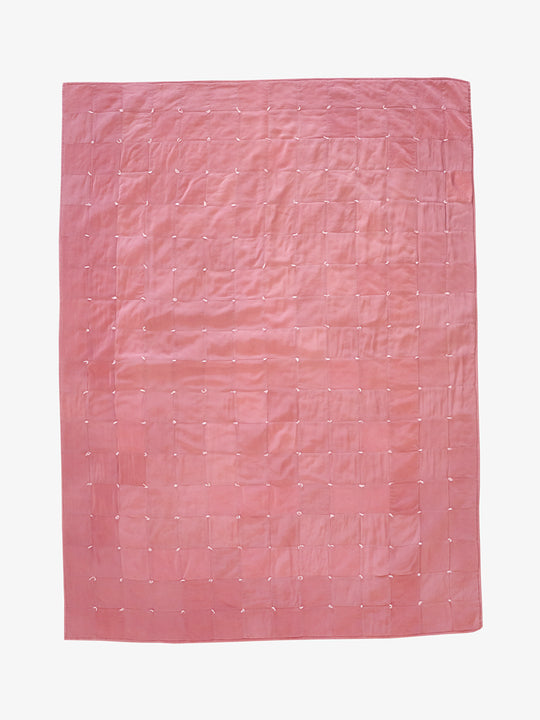 Hand-dyed dusty rose silk patchwork quilt by Lily Raskind, shown flat with square grid stitching detail.