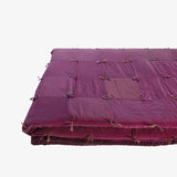 Folded view of Lily Raskind Smoke Brush hand-dyed silk blanket showing quilt thickness and tied patchwork detail.
