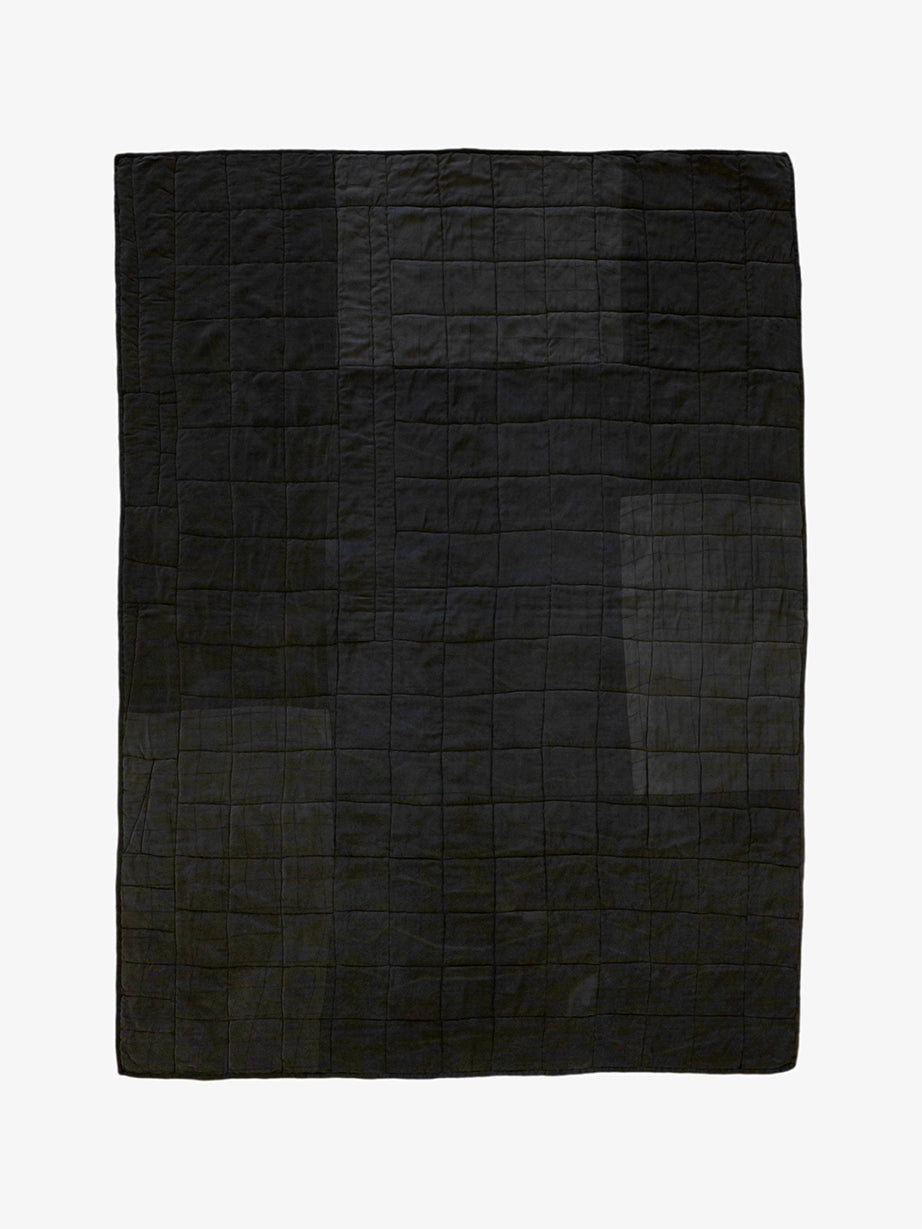 Back view of handmade silk patchwork quilt by Lily Raskind showing solid black stitched grid pattern
