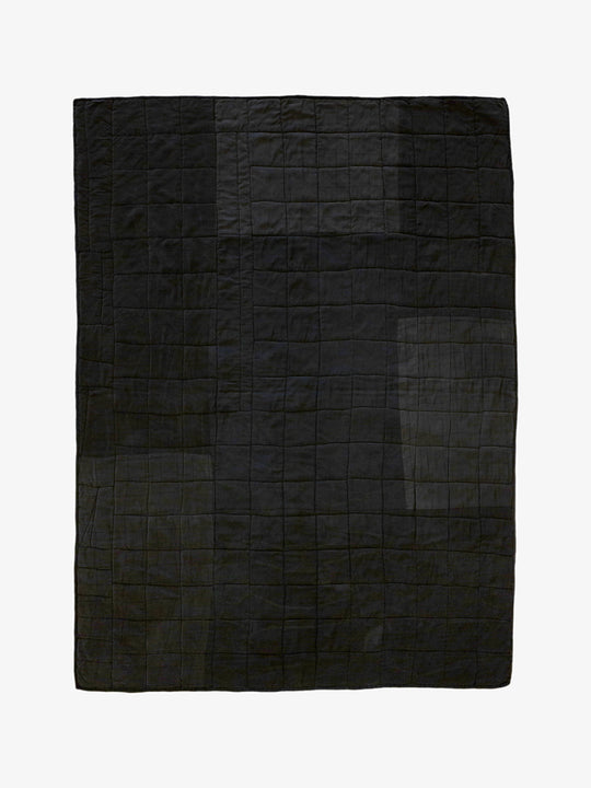 Back view of handmade silk patchwork quilt by Lily Raskind showing solid black stitched grid pattern