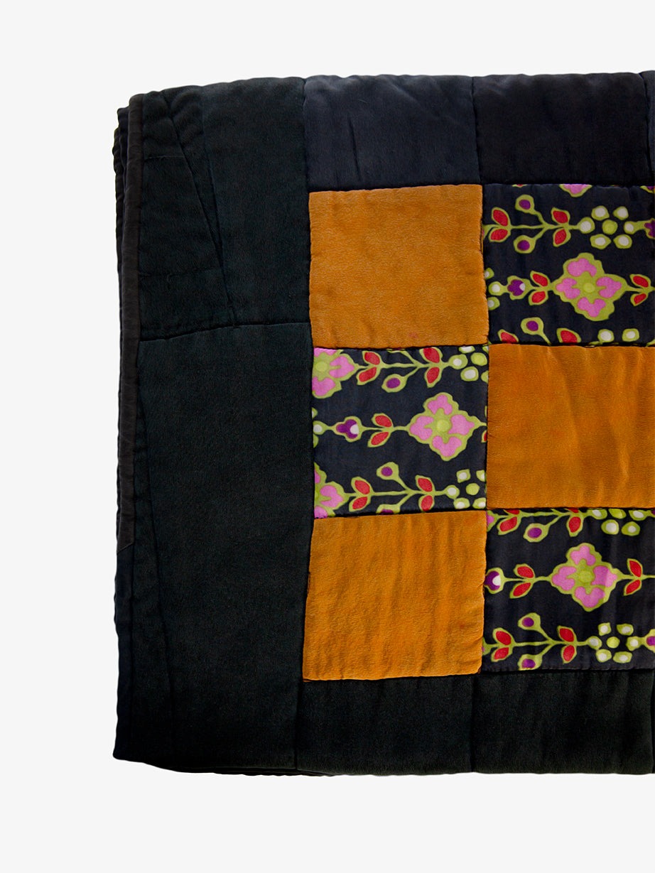 Close-up of silk patchwork quilt by Lily Raskind displaying fabric texture and square design.