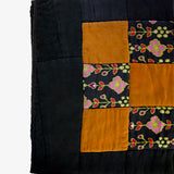 Close-up of silk patchwork quilt by Lily Raskind displaying fabric texture and square design.