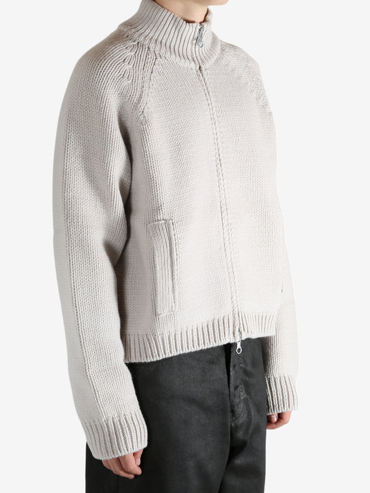 White cardigan worn by a person, showing the cardigan's fit