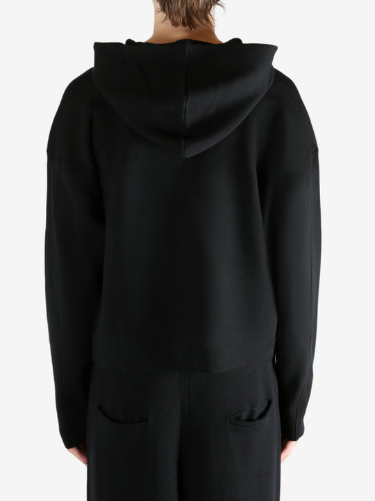 Black knitwear worn by a person, showing the knitwear's fit