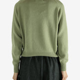 Green knitwear worn by a person, showing the knitwear's fit