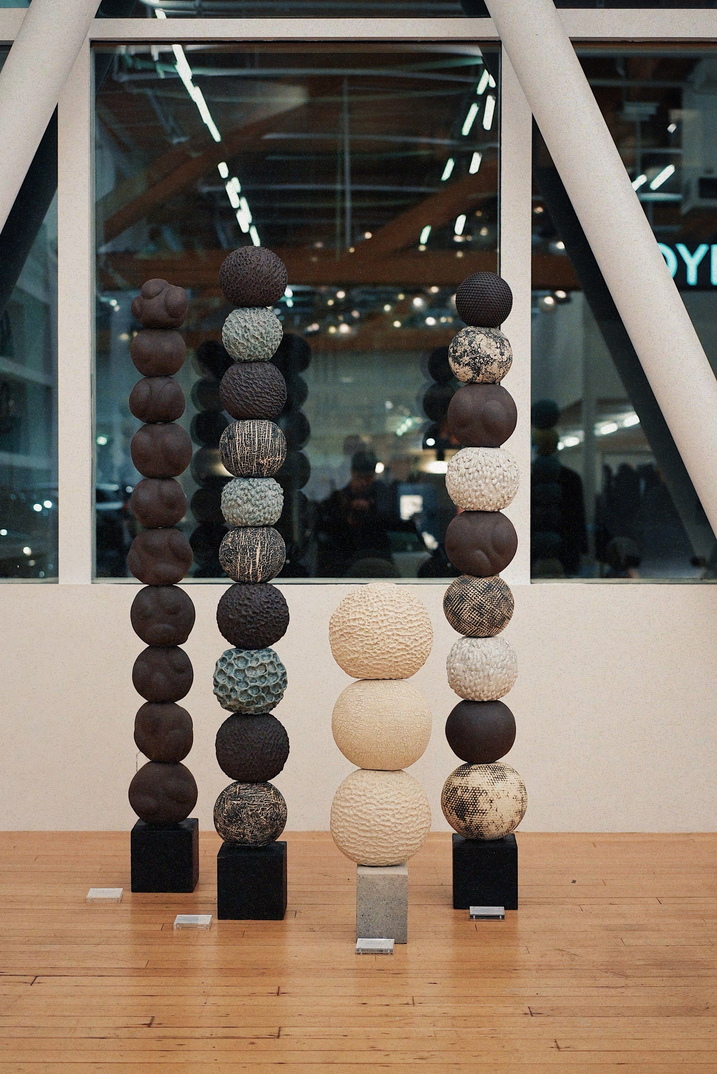 Four vertical stacked ceramic sculptures by Ann Shure in stoneware, terracotta, earthenware, and porcelain on concrete and steel bases.