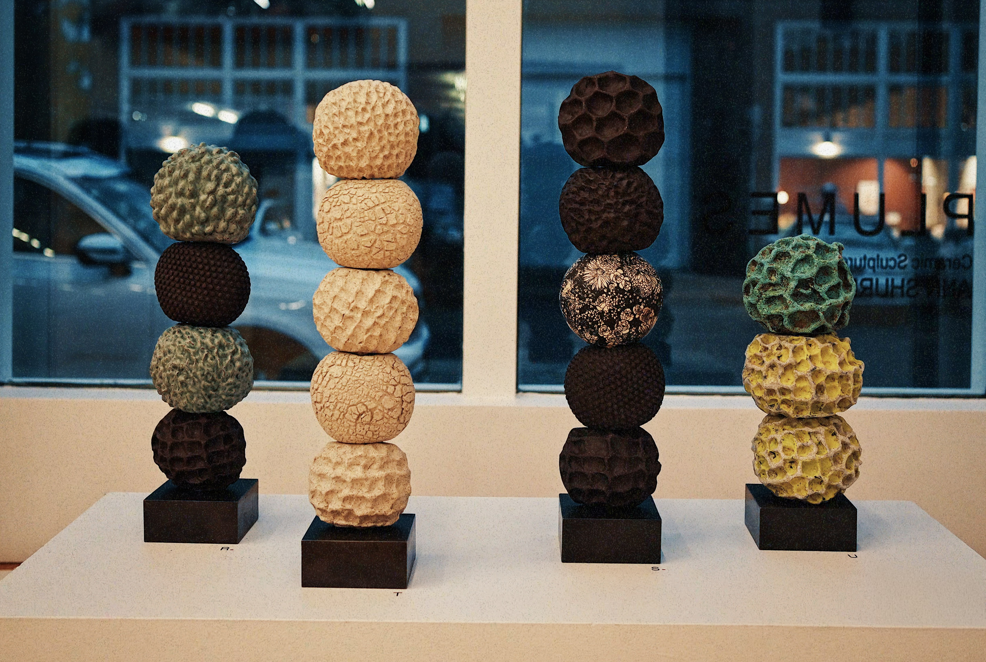 Four vertical stacked ceramic sculptures by Ann Shure in stoneware, earthenware, and terracotta on steel and concrete bases