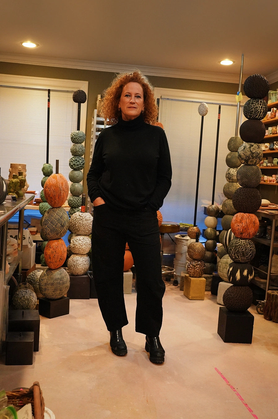 Ceramic artist Ann Shure in studio with stacked sculptures and works in progress